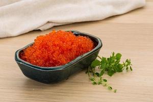 Red caviar in a bowl on wooden background photo