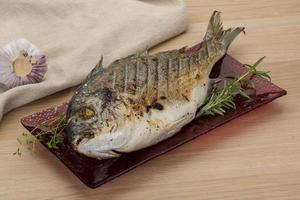 Grilled dorado on the plate and wooden background photo