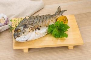 Grilled dorado on wooden board and wooden background photo