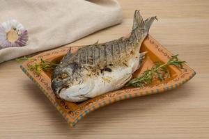 Grilled dorado on the plate and wooden background photo