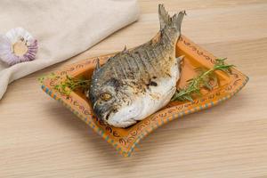 Grilled dorado on the plate and wooden background photo