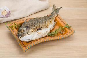 Grilled dorado on the plate and wooden background photo