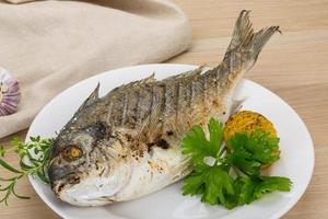 Grilled dorado on the plate and wooden background photo