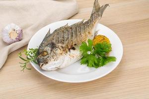 Grilled dorado on the plate and wooden background photo