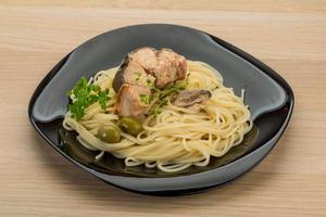 Pasta with salmon on the plate and wooden background photo