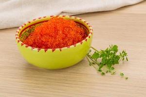 Red caviar in a bowl on wooden background photo