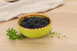 Black caviar in a bowl on wooden background photo