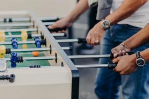 Best male friends play table football or kricker, feel heat in anticipation of victory. Sport, friendship, entertainment, leisure concept photo