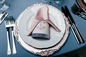 Empty plate with napkin, forks and knives on light blue tableclothes. Beautiful table setting on blue background. Festive table served for banquet. Beautifully organized event. Event in restaurant photo