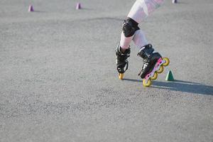 Cropped shot of teenager rollerblades on asphalt, has trial, wears rollerblade and protection on knees. Active lifestyle, leisure and hobby concept photo