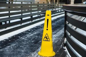 ser consciente de la carretera resbaladiza. señal de superficie amarilla resbaladiza. señal de piso mojado. concepto de formación de hielo. enfoque selectivo. pendiente resbaladiza. cuida tus pasos, por favor foto