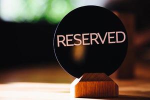 Reserved sign on restaurant table. Booked desk in cozy cafe against blurred background. Booking and reservation concept. Book seat for costumer. photo