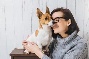 una foto de una joven atractiva abraza a su perro favorito, toca con la nariz, expresa un gran amor por la mascota. perro leal tiene buenas relaciones con el anfitrión. amistad, relaciones, animales y personas