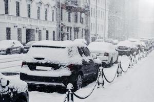 carretera cubierta de nieve y transporte. ciudad paralizada después de fuertes nevadas. coches cubiertos de nieve espesa. clima invernal y concepto de desastre natural foto