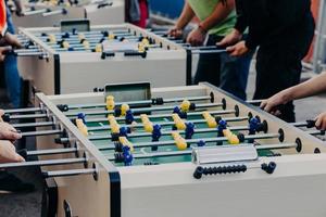 People, entertainment and recreation concept. Unrecognizable friends have fun together, play table football or kicker, rest in pub outdoor photo