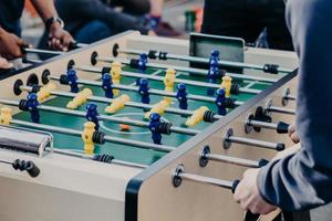 Men colleagues enjoy table soccer game after working day, have free time, like to play board games. Rest of young people during spare time photo