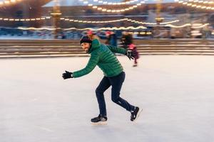 Male in speed demonstrates his skills of skating, has fun on ring, feels sure and confident on ice, spends free time outdoor, enjoys winter vacations, being photographed in movement photo