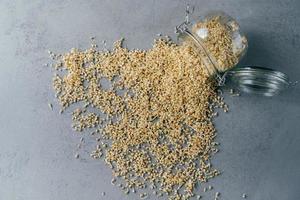 Sprouted buchwheat spilled from glass jar on grey background. Vegan organic sprouts. Eco products. Dieting and healthy nutrition concept photo
