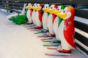 coloridas figuras de pingüinos utilizadas por los patinadores principiantes para no caer sobre el hielo cubierto de nieve, equipo especial para enseñar a patinar. ayudantes de patinadores para mantener el equilibrio en el hielo foto