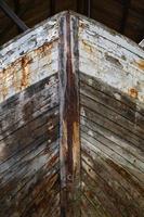 A head-on image of the bow of an old boat pulled up on land. photo