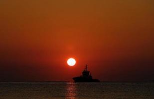 A ship leaving port at sunrise photo