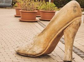 Wooden shoe as a decoration in a shopping street. Fashion from wood. Oversized shoe. photo