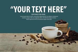 taza de café caliente con granos de café en la mesa de madera y fondo azul marino con espacio de copia para el texto. foto