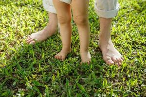 Closeup portrait of a mother helping baby to walk on grass photo