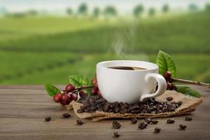 Hot coffee cup with fresh organic red coffee beans and coffee roasts on the wooden table and the black background with copyspace for your text. photo