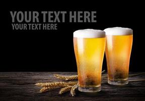 Cold beer with wheat on wooden table. Glasses of light beer on the isolate black  background with copy space. photo