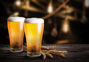 vasos de cerveza ligera con cebada en el bar. dos vasos de cerveza con trigo en la mesa de madera