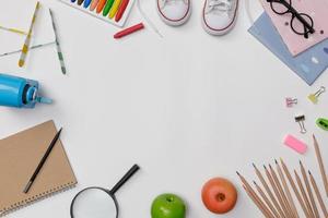 flatlay creativo de mesa blanca de educación con libros de estudiantes, zapatos, lápices de colores, anteojos, espacio vacío aislado en fondo blanco, concepto de educación y regreso a la escuela foto