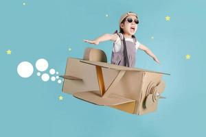 Asian little child girl playing with cardboard toy airplane handicraft isolated on blue long banner with copy space for your text, Creative with family and dreaming of flying concept photo