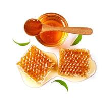 Honeycomb with jar and honey spoon and leaf isolated on white background photo