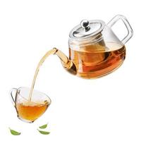 Jug pouring hot tea into glass cup with green tea leaves in the air, Healthy products by organic natural ingredients concept, Empty space in studio shot isolated on white background photo