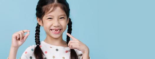Asian child's hand shows the fallen out small white milk teeth close-up, Dentistry and Health care concept, Empty space isolated on blue background photo