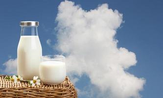 A bottle of rustic milk and glass of milk on wicker on a blue sky background, tasty, nutritious and healthy dairy products photo
