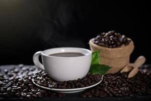 Hot coffee cup with coffee beans on the wooden table photo