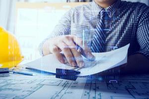 business hand working and laptop with on on architectural project at construction site at office desk in office photo