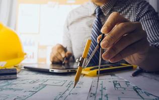 Two colleagues discussing data working and tablet, laptop with on on architectural project at construction site at desk in office photo