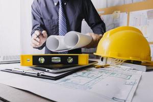 Two colleagues discussing data working and tablet, laptop with on on architectural project at construction site at desk in office photo