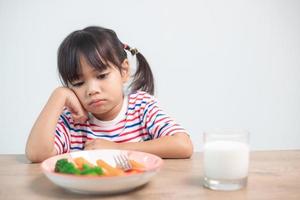 Nutrition  healthy eating habits for kids concept. Children do not like to eat vegetables. Little cute girl refuses to eat healthy vegetables. photo