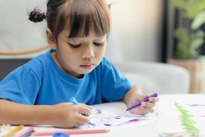 Cute little girl paints and tinkers with colored pencils and scissors photo