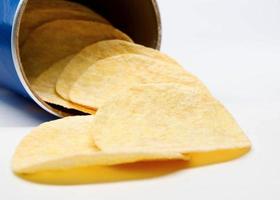 Potato chips are poured out of a can of chips. photo