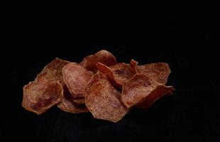 Meat chips on a black background. Beautiful placer of thin slices of dried meat. photo