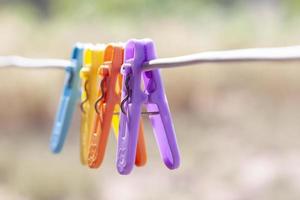 clips de ropa de plástico de varios colores en el cable sobre fondo de naturaleza borrosa. foto