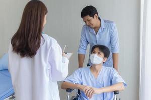 An Asian woman doctor is checking and talking with a man patien photo