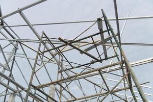 Scaffolding for support construction of building a house. Steel roof structure connected to cement columns under the sky. photo