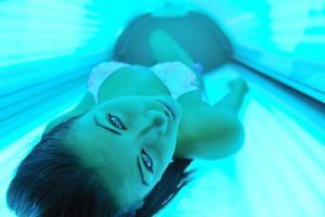 Beautiful young woman tanning in solarium photo