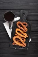 churros caseros con chocolate sobre un fondo rústico de madera oscura. foto